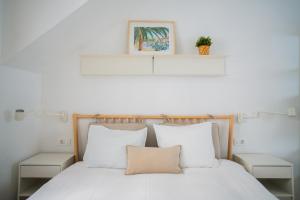 Schlafzimmer mit einem Bett mit weißer Bettwäsche und weißen Kissen in der Unterkunft Blu Riva Hvar in Hvar