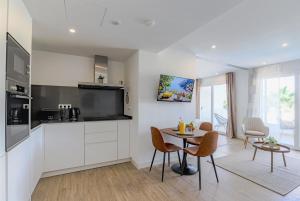 Una cocina y una sala de estar con mesa y sillas. en Brand New Stylish Retreat in Alcazaba Lagoon - Estepona, en Estepona