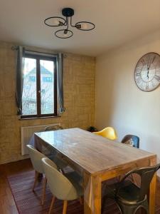 ein Esstisch mit Stühlen und einer Uhr an der Wand in der Unterkunft La Colombe in Beblenheim + 7 Fotos