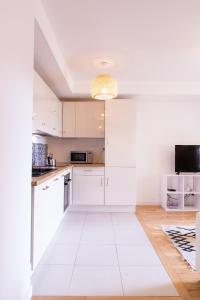 a kitchen with white cabinets and a white floor at Appart Le Lully in Versailles