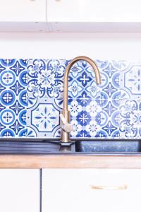 a kitchen sink with a blue and white wallpaper at Appart Le Lully in Versailles +26 photos