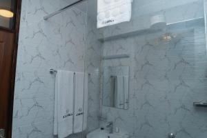 uma casa de banho com paredes em mármore branco e um WC. em Amoria Boutique Hotel em Kiambu