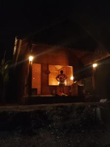 a man standing in front of a house at night at Tetebatu River Side BUNGALOWs in Tetebatu