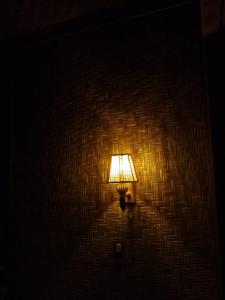 a lamp attached to a brick wall with a light on it at Tetebatu River Side BUNGALOWs in Tetebatu