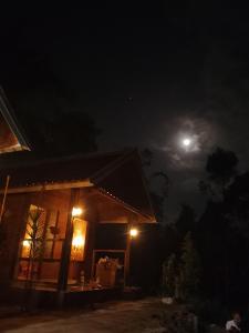a house at night with the moon in the sky at Tetebatu River Side BUNGALOWs in Tetebatu