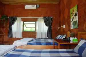 a bedroom with two beds and a table and a window at Ha Giang Eco Bungalow in Ha Giang +178 photos