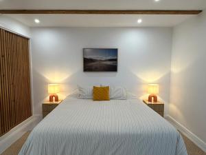 a bedroom with a white bed with two lamps at Casa Amélia in Feteira Grande