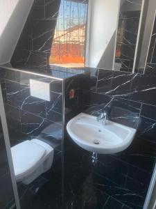 a black tiled bathroom with a sink and a toilet at Pension in Warin