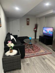Una sala de estar con un sofá negro y un televisor. en Basement, en Brampton