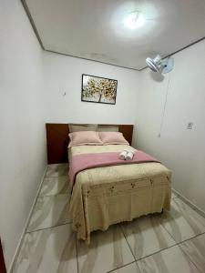 a small bedroom with a bed with pink sheets at Serraruna House no centro histórico in Araruna