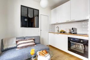 a living room with a couch and a kitchen at Le Marais & Place des Vosges - Paris Vacation Rentals in Paris