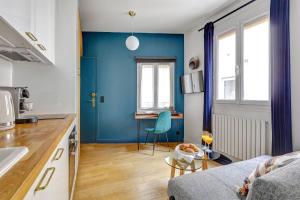 a blue kitchen with a couch and a table at Le Marais & Place des Vosges - Paris Vacation Rentals in Paris