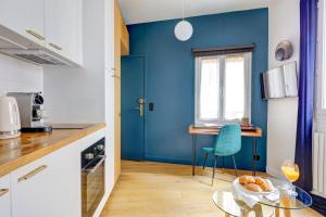 a blue kitchen with a glass table and a blue wall at Le Marais & Place des Vosges - Paris Vacation Rentals in Paris +12 photos