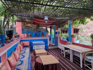a patio with chairs and tables and a pergola at Maison d'hôte Riad Todra in Tinerhir