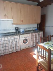 a kitchen with a washing machine and a table at Casa Cordovilla in Sequeros