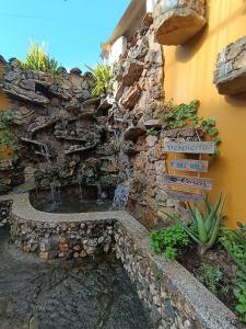 Estación El SaltoにあるHospedaje La Fuenteの建物の前の滝のある石垣