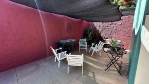a patio with chairs and a table and a pink wall at Quartos Villa do Aconchego Casa compartilhada in São João da Boa Vista