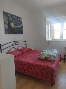 een slaapkamer met een bed met een rode sprei bij Casa al mare in centro a 100 metri dalla spiaggia con terrazza in Torre Santa Sabina