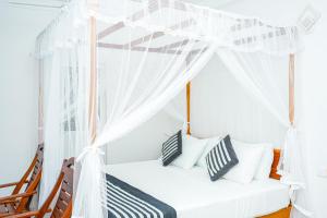 a white canopy bed in a room with chairs at PEACEFUL GREEN VILLA in Unawatuna