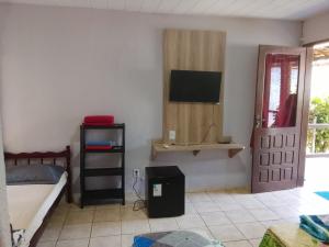 a bedroom with a bed and a television on the wall at Pousada Encantos de Paripueira in Paripueira