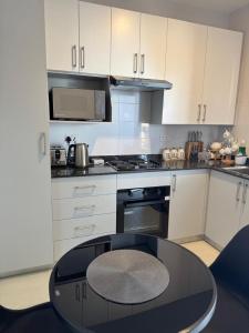 a kitchen with white cabinets and a glass table at Kastina Suites at The Fig in Gaborone
