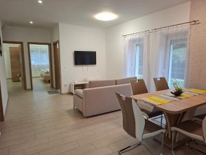 a living room with a table and a couch at Napsugár Wellness Apartman in Újudvar