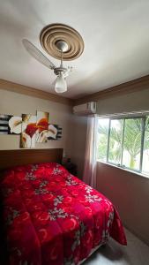 a bedroom with a red bed and a ceiling fan at Paraíso Tropical em Porto Seguro in Porto Seguro