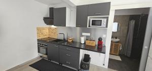 a kitchen with black cabinets and a microwave at Studio cosy de 28m2 - Quartier Les Cultures in Saint-Laurent du Maroni
