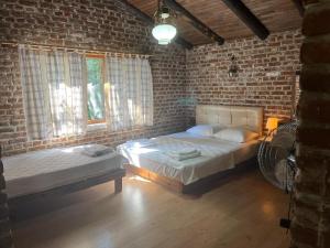 a bedroom with two beds and a brick wall at Kybele Nature Life in Edremit