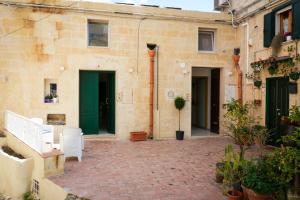 a courtyard with white chairs and a building with green doors at MAGNIFICAT luxury rooms in Matera