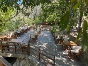 a row of wooden tables and chairs under a tree at Kybele Nature Life in Edremit