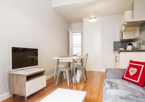 a living room with a couch and a table with a television at Les Loges des Chalets in Toulouse