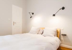 1 dormitorio con 1 cama blanca y 2 luces en la pared en Les Loges des Chalets, en Toulouse