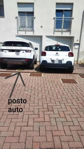Dos coches blancos estacionados frente a un edificio en Holiday House Iolo, en Prato