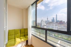 上海市にある梧舍壹号 外滩百年公寓B&B -Riverside Grace Suites on the bund and metro stationの緑のソファと大きな窓が備わる客室です。