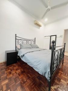 a bedroom with a black bed and a wooden floor at Roomah Puteh in Shah Alam