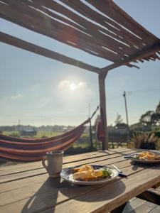 a wooden table with plates of food and a cup of coffee at Lalau Casa de Playa in Chapadmalal