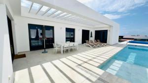 een wit huis met een zwembad en een tafel en stoelen bij Pipa Costa in Costa Teguise