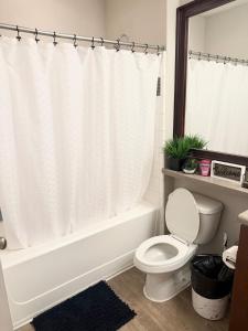 y baño con aseo y bañera con cortina de ducha. en Luxe Haven, en Atlanta