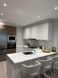a kitchen with white cabinets and a kitchen island with chairs at Refugio moderno céntrico in Vigo