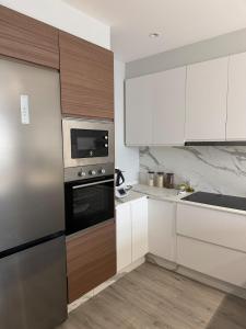 a kitchen with white cabinets and a stainless steel refrigerator at Refugio moderno céntrico in Vigo +3 photos