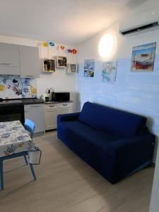 a living room with a blue couch and a kitchen at La Terrazza di Simo in Trinità dʼAgultu
