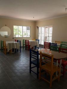 a dining room with tables and chairs and windows at Pousada Casarrara in Itaberaba