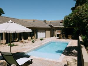 a swimming pool with a chair and an umbrella at Kokon Boutique Guesthouse in Somerset West