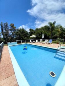 a large swimming pool with chairs and umbrellas at La Rosa del Azafrán - Alojamiento Rural - Ranchos de Vacaciones en Entre Ríos in San José