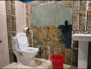 un baño con inodoro y lavabo en Atulyam Farms and Stay, en Shogi