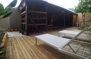 un patio avec un banc blanc et une terrasse en bois dans l'établissement Maison 6 personnes au pieds des montagnes à l'Entre-deux, à Entre-Deux
