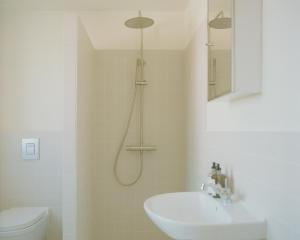 ein Badezimmer mit Dusche, Waschbecken und Toilette in der Unterkunft Løkkenshus Rooms and Apartments in the Heart of Løkken in Løkken
