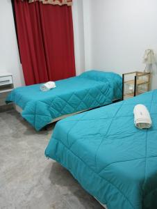 two blue beds in a room with a red curtain at Dionycio in Cafayate