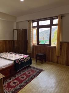 a bedroom with a bed and a large window at Shenga Homestay in Ravangla